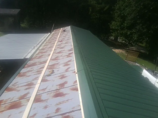Old rusted panels beside newly installed green metal roofing — Wind Damage Roof Repair by Roofing Brothers in Oakley