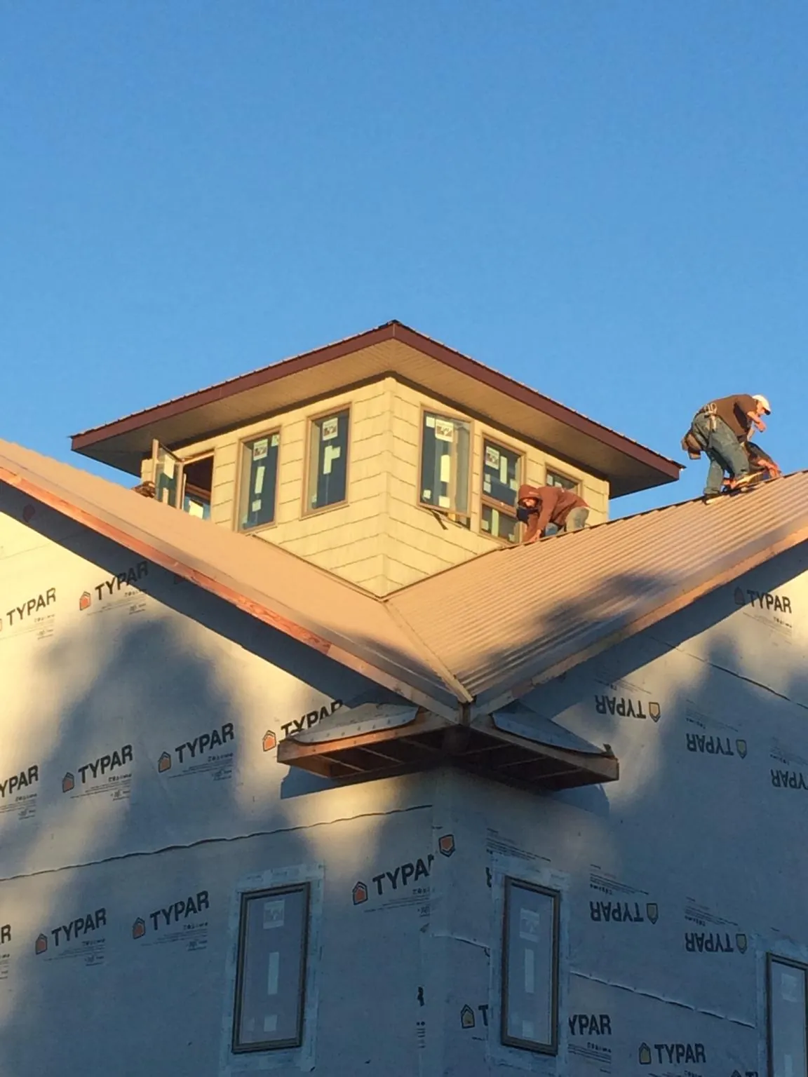 Roofers working around a rooftop cupola on a new metal roof at sunset — Roof Waterproofing in Oakley by Roofing Brothers